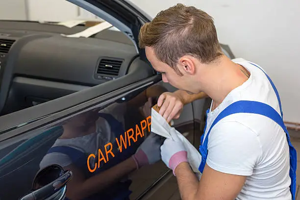 Photo of A car branding specialist applying a logo to a car
