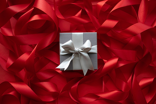 Silver color gift box on red ribbon background.