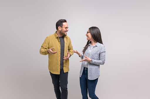 Cheerful young colleagues laughing and discussing business ideas while standing on white background