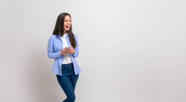 istock Ecstatic female professional messaging online over smart phone and laughing against white background 1876722701