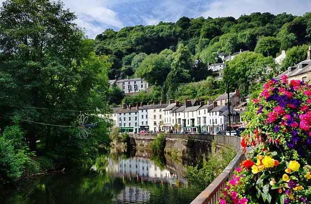 View of the River Derwent flowing through Matlock Bath in Derbyshire with trees and flowers