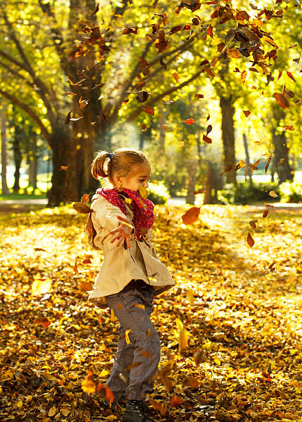 istock Cute girl is playing with autumn leaves 187675050
