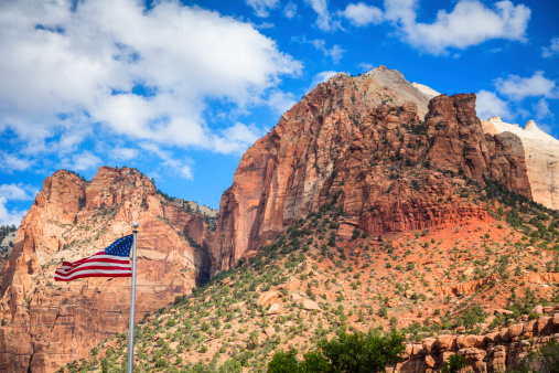 The US flag against the red sandstone cliffs of Zion Canyon in Zion National Park, Utah.