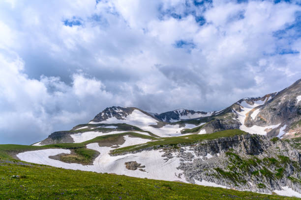 istock Scenic panoramic view of idyllic rolling hills landscape with blooming meadows and snowcapped alpine mountain peaks in the background on a beautiful sunny day. 1876785151