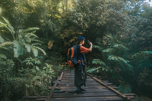 Asian Chinese young woman photographing with smartphone when hiking during weekend morning