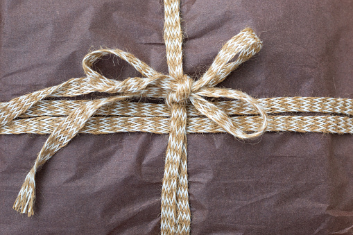 The gift is packed in brown paper and tied with a ribbon.