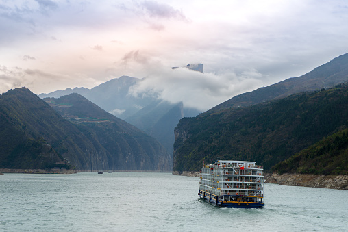 A lone boat traverses the tranquil waters of the Yangtze River, amidst the misty mountains of Fengjie County, China, captured on March 17, 2018.