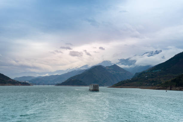 A lone boat traverses the tranquil waters of the Yangtze River, amidst the misty mountains of Fengjie County, China, captured on March 17, 2018.