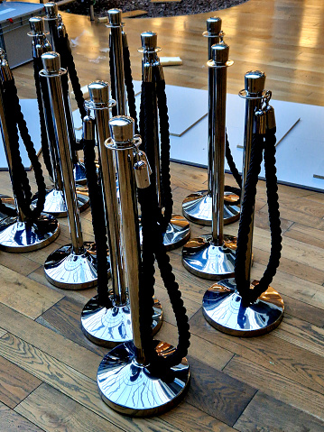 Demarcation post for rope cylinder, polished stainless steel. Fencing posts with a rope serve as a mobile barrier to delimit space barrier post by Christmas tree in office school building corridor