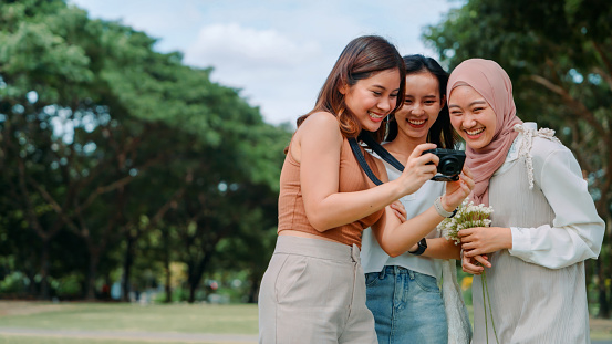 Snapshot of Friendship: Diverse Female Friends Capture Moments with a Point-and-Shoot Camera Stroll in the Park