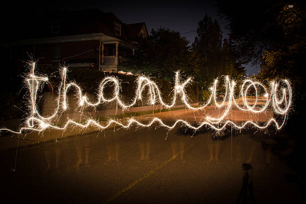 Lightpainting: Thank you The expression "Thank you" in cursive writing (script) created using a long exposure light painting photography technique on an urban background lightpainting stock pictures, royalty-free photos & images