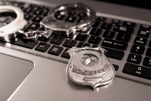 Cyber Crime: Handcuffs and police badge on laptop. White collar crimes. Identity theft or corporate fraud. police badge on desk stock pictures, royalty-free photos & images