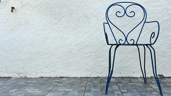 Blue heart-shaped chair in front of a house with white walls