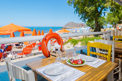 Restaurant with Agia Marina Beach View in Chania, Crete. Greek Islands. Crete Island Beach with Delicious Greek Salad.
