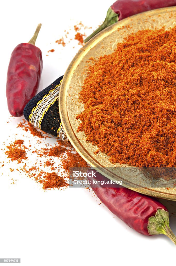 Chili red pepper powder isolated on white background Oriental copper plate with dried crushed chili red pepper powder and whole dried chili peppers isolated on white background. Oriental spicy food concept. Asia Stock Photo
