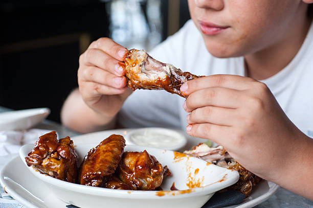 caucasian 12 years old child holding a chicken buffalo wing