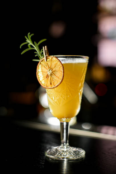 istock Selective focus of illuminated old-fashioned glass with warming yellow alcoholic cocktail on bar counter at dark bar 1876967671