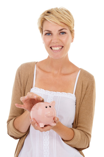 A gorgeous young woman putting a coin into her piggybank while isolated on a white background