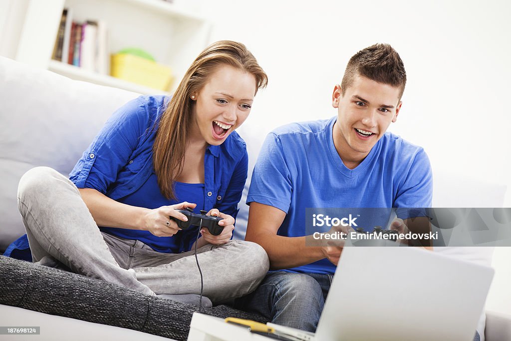 Jeune couple jouant à un jeu multiplayer sur ordinateur portable, - Photo de Activité libre de droits
