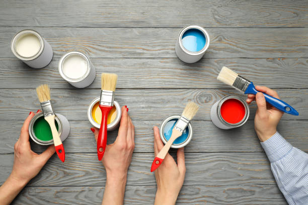 istock Jars with paints, brushes and hands on wooden background, top view 1876990518