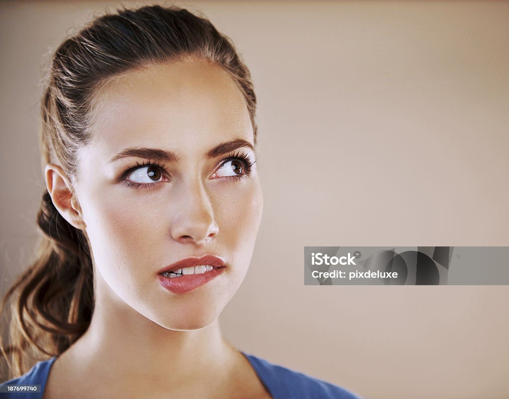 I don't know how to answer that Attractive woman biting her lip isolated on beige Biting Lip Stock Photo