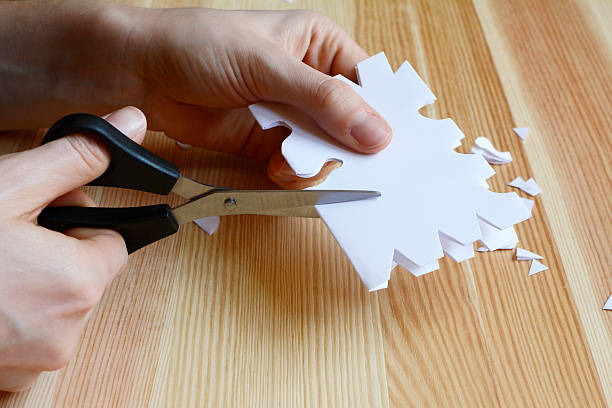используя ножницы для обрезки в виде бумажные снежинки - cut or torn paper стоковые фото и изображения