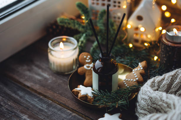 istock Christmas home aromatherapy. Aroma diffuser with pine extract, organic essential oil, cedar and spruce cone, cinnamon, anise, vanilla scent, candles, wooden table. Cozy atmosphere, winter inspiration 1877016575