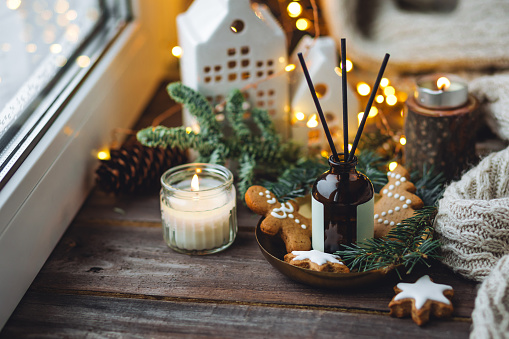 Christmas fragrance, cinnamon, anise, vanilla. Home comfort, coziness, aromatherapy. Winter time. Cozy Scandinavian interior with burning candles, aroma perfume reed diffuser in the bedroom