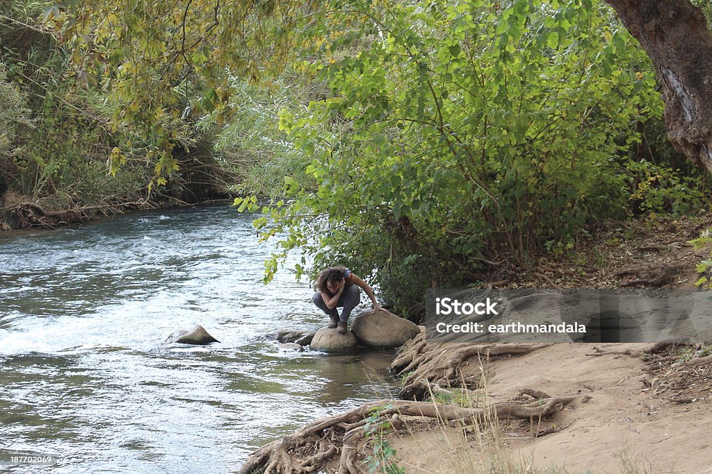 Israel Young female on the banks of Snir Stream Young female looking into the water on the banks of the Hasbani or Snir Stream Adult Stock Photo