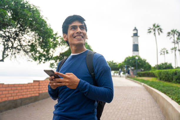Young Hispanic man texting a message while strolling in Faro dela Marina, Miraflores boardwalk, Peru