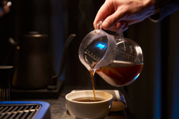 istock Coffee maker pouring hot aromatic Americano into cup 1877035056