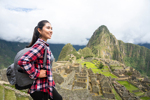 Mid-shot side view of young Latin woman enjoying the view while hiking in Sacred City of Machu Picchu, Peru