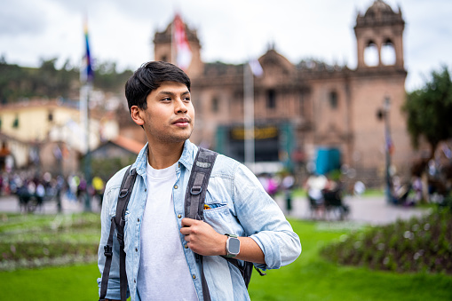 Mid-shot front view of young man sightseeing in Plaza Mayor, Cusco, Perú