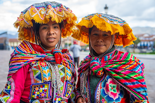 Mid-shot front view of two indigenous Peruvian women looking at camera in Plaza Mayor, Cusco, Perú
