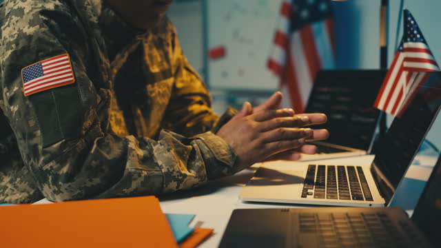 African American U.S. intelligence officer typing on laptop in office, desk job