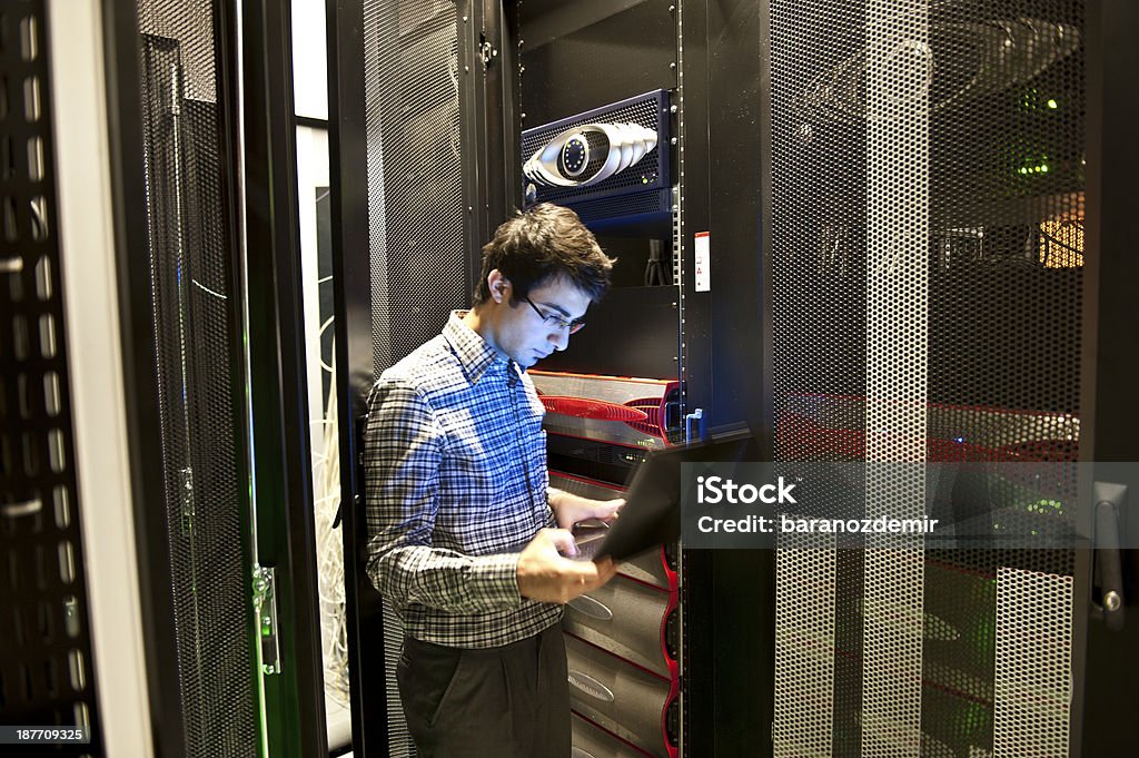IT Programmer An IT technician programming computer equipment in a server room Server Room Stock Photo