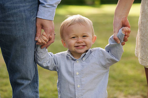 istock Toddler Holding Hands with Parents 187714074