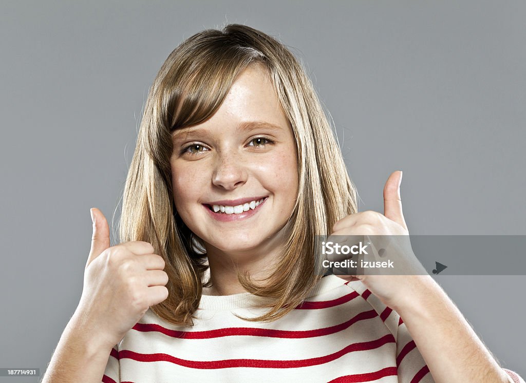 Happy cute girl Portrait of cute girl wearing striped blouse smiling at camera with thumbs up. Studio shot. Teenage Girls Stock Photo