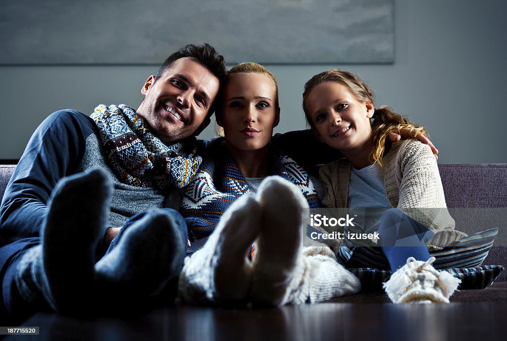 Happy Family, Winter Portrait Winter portrait of happy family wearing woolen scarfs and socks, embracing and smiling at camera. Dark tones. Dark Stock Photo