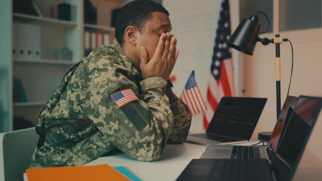 U.S. army officer working on laptop in office, frustrated with difficult task