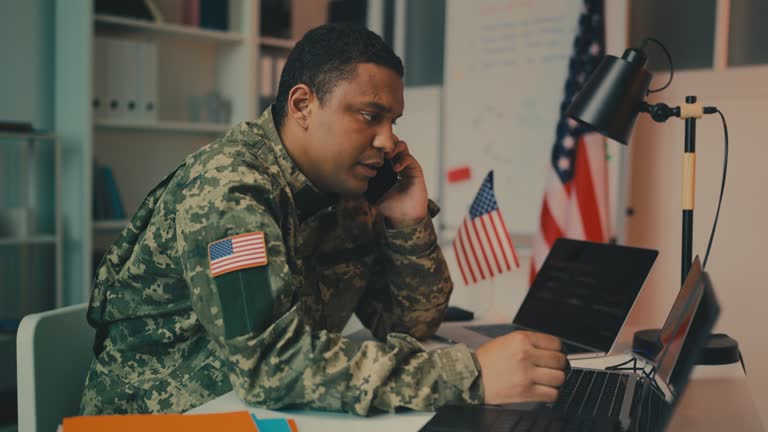 Serious U.S. army officer talking on phone in his office, giving out orders