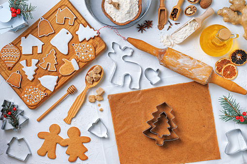 Christmas gingerbread different shaped with sugar icing and ingredients for gingerbread on wooden table, top view, flat lay