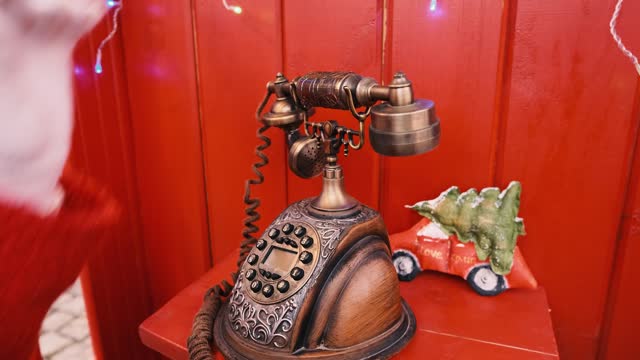 Vintage telephone in a red street booth. A child's hand hangs up the phone.