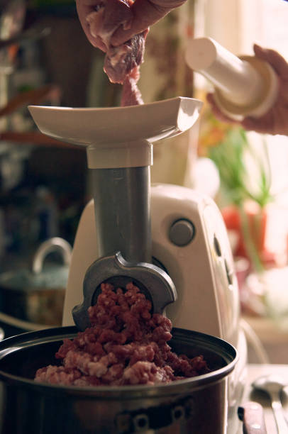 istock Putting morsels of meat in grinder machine with hand 1877195533