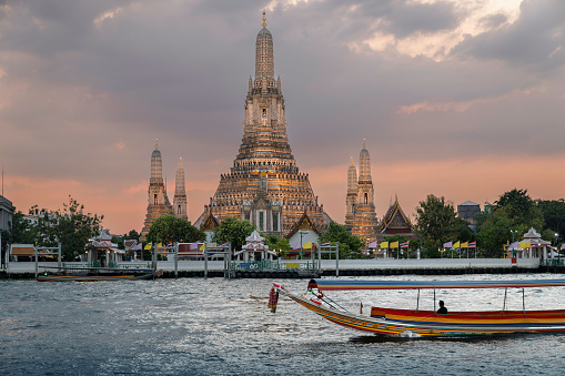 Boat river taxi passing by Wat Arun on the Chao Phraya river in Bangkok