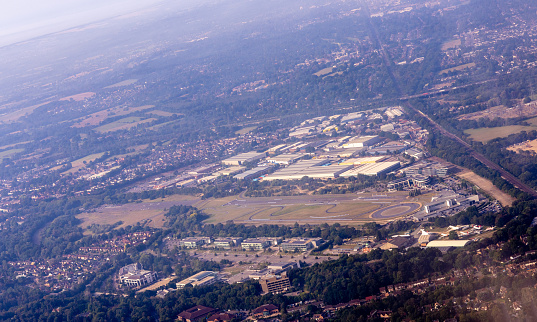 A large airport seen from above as an aircraft flies over.