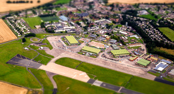 A large airport seen from above as an aircraft flies over.
