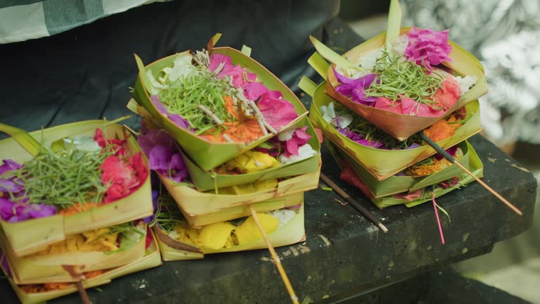 Wicker baskets with flowers and burning incense sticks. Canang Sari daily offerings made by Balinese Hindus to thank God Deva in praise and prayer.