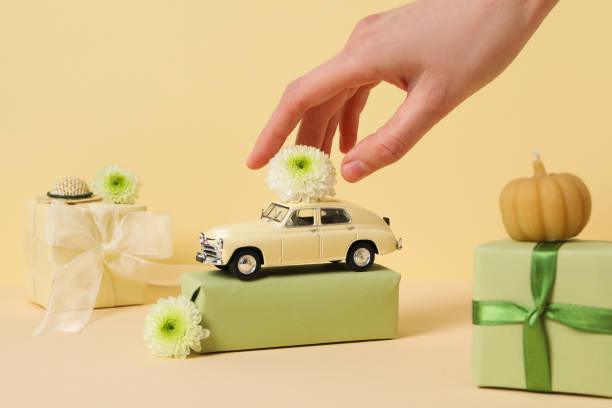 Toy retro car with a gift, a flower and a pumpkin