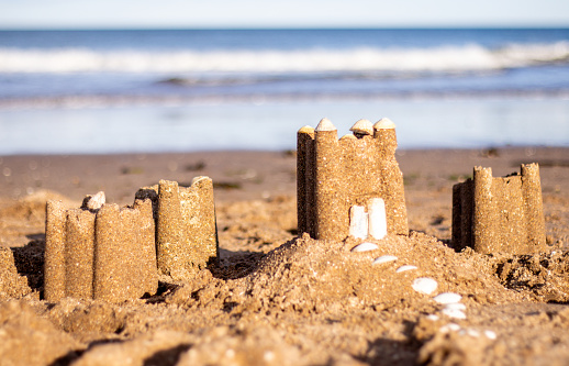 A sandcastle made on a beach during the summertime, with the sea in the background.